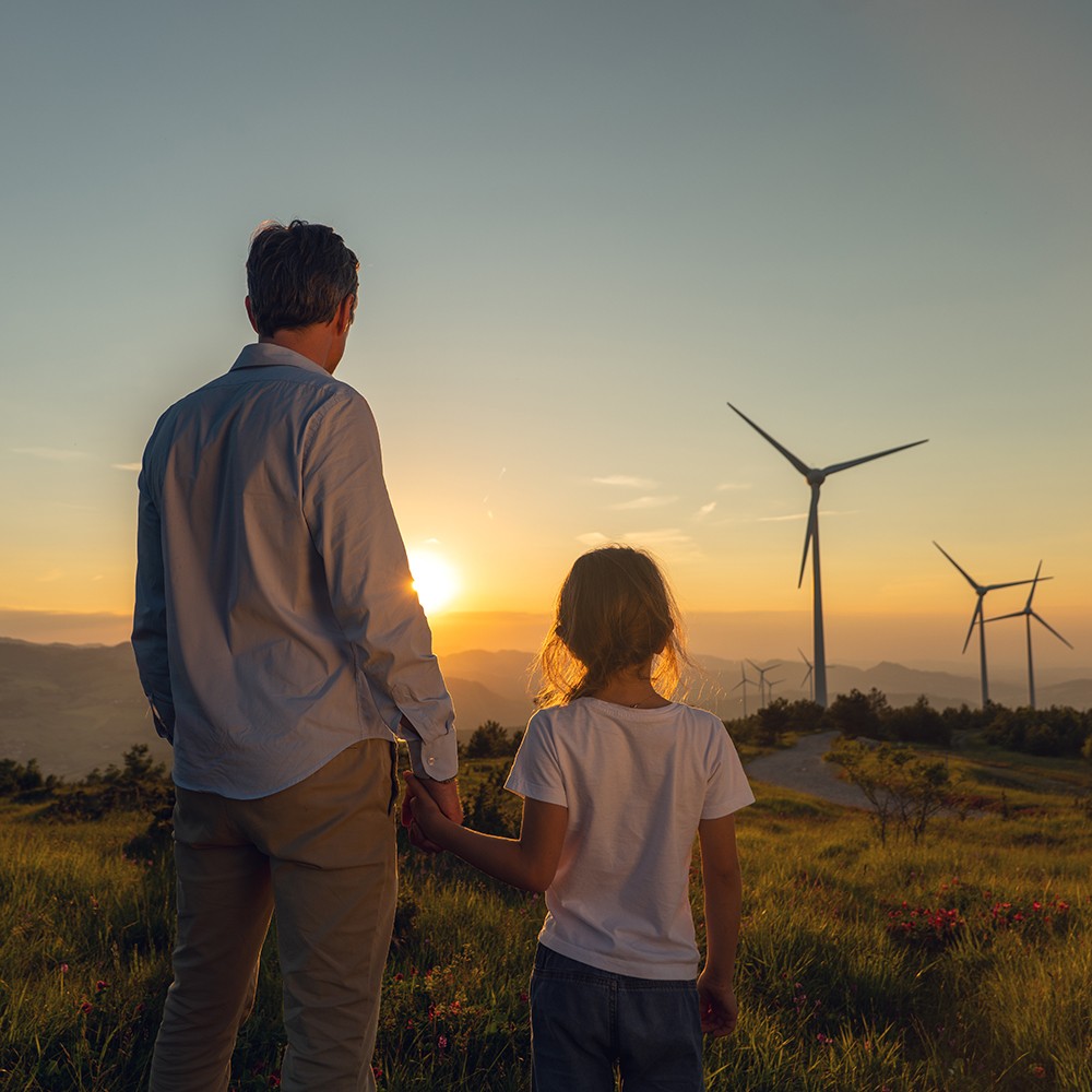 Vater und Tochter schauen auf Windpark im Sonnenuntergang